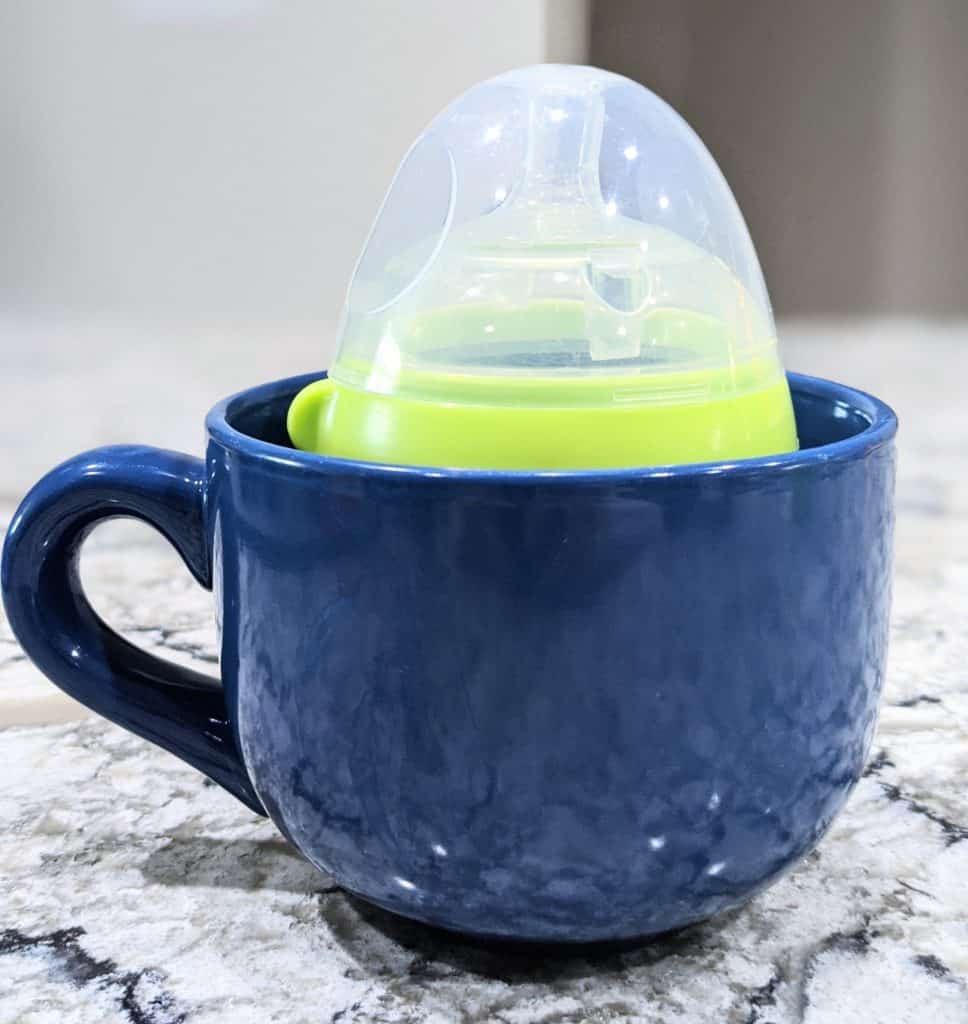 Photo of baby bottle in a mug of warm water