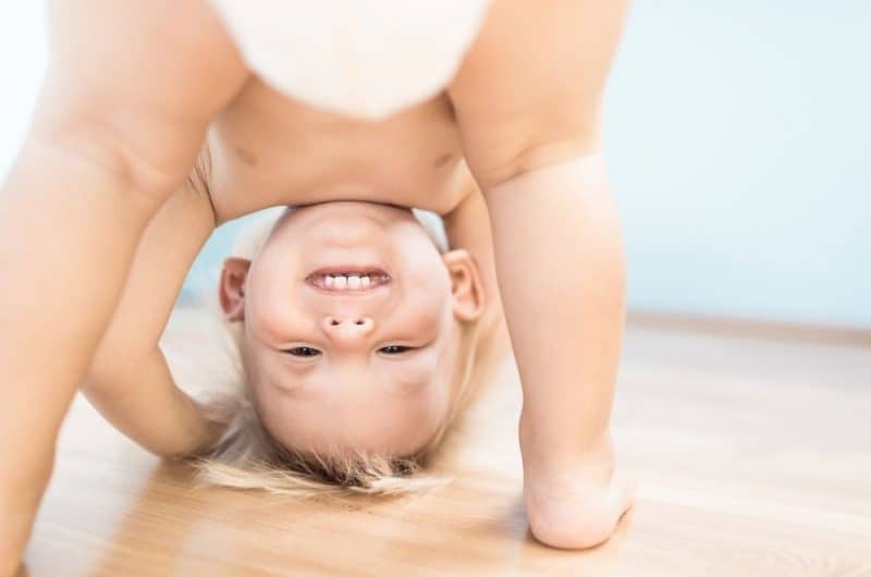 toddler boy bending over and looking through legs and smiling