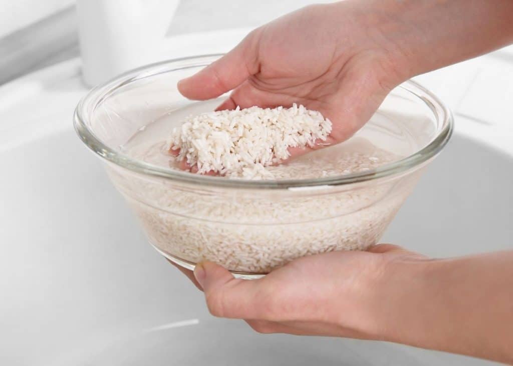 Hand rinsing rice in water to make rice water