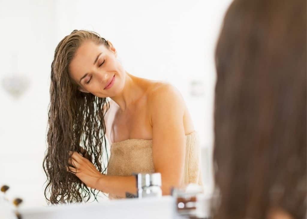 woman applying rice water rinse for postpartum hair loss