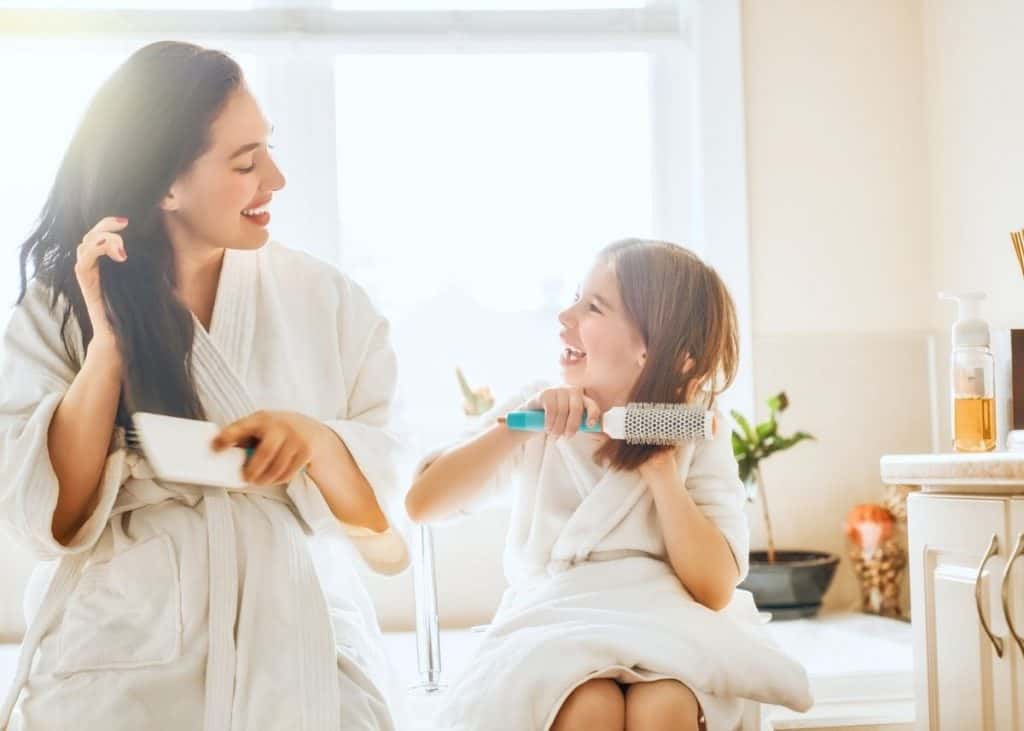 mother and daughter combing hair after applying rice water to prevent postpartum hair loss