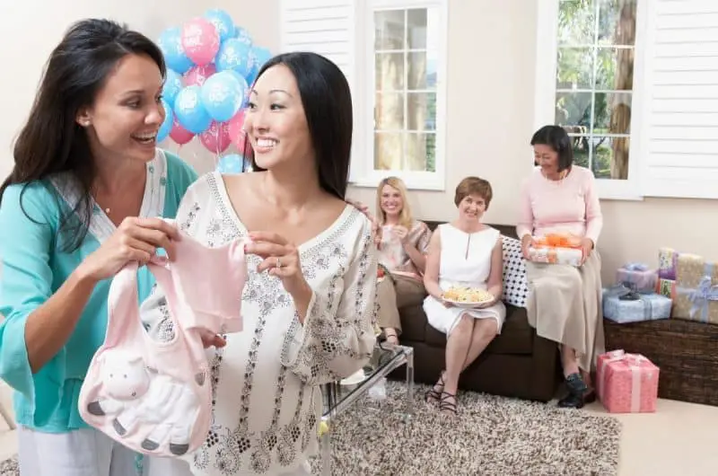 women at a display baby shower fawning over cute clothes