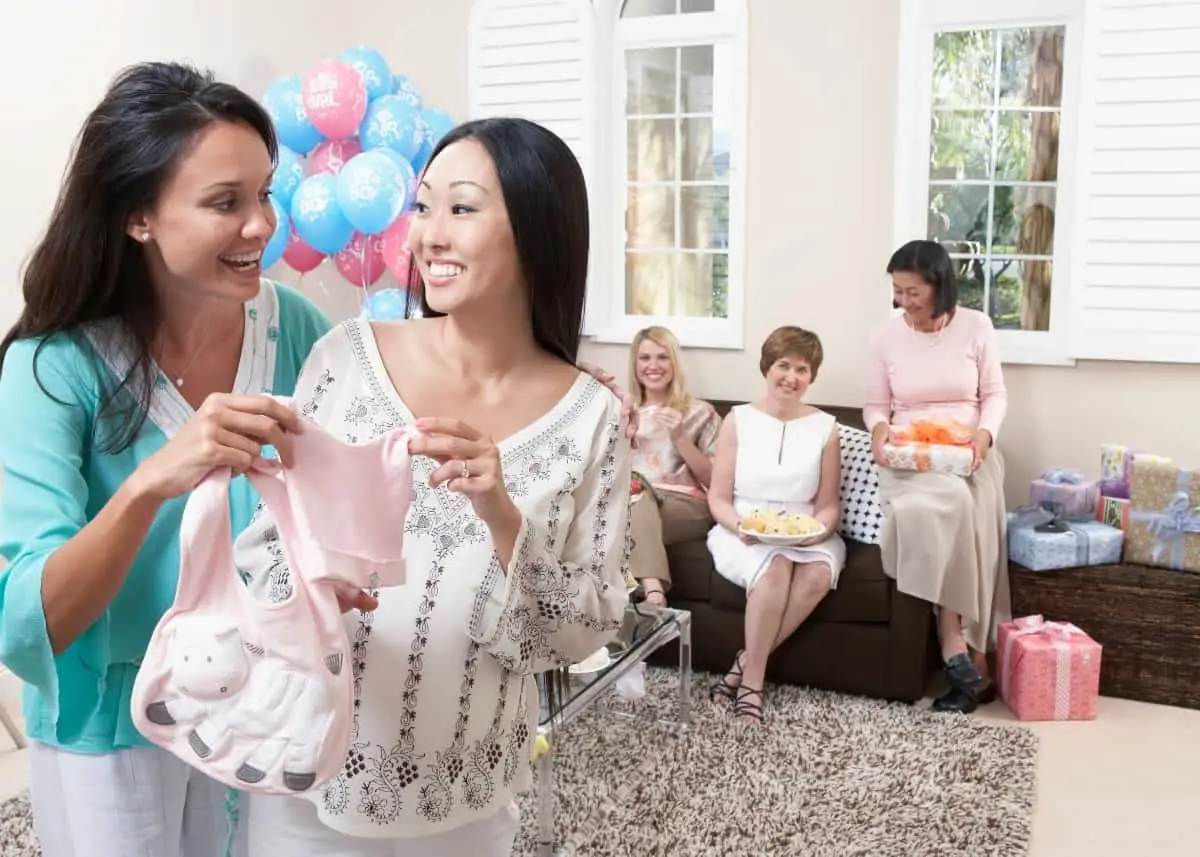 women at a display baby shower fawning over cute clothes