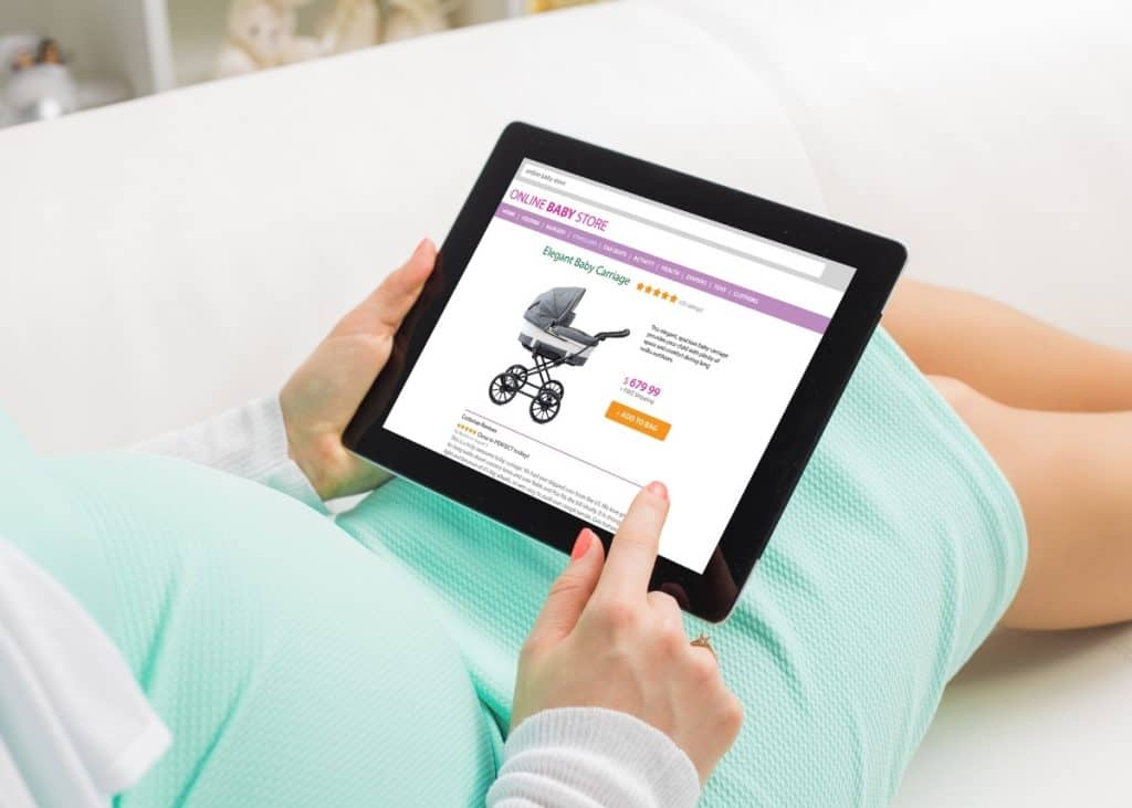 pregnant woman online shopping for baby stroller on tablet