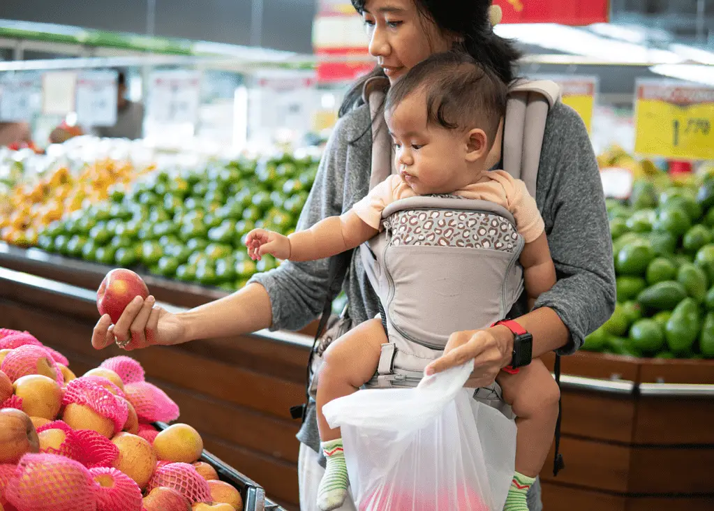 mom carrying baby in carrier grocery shopping