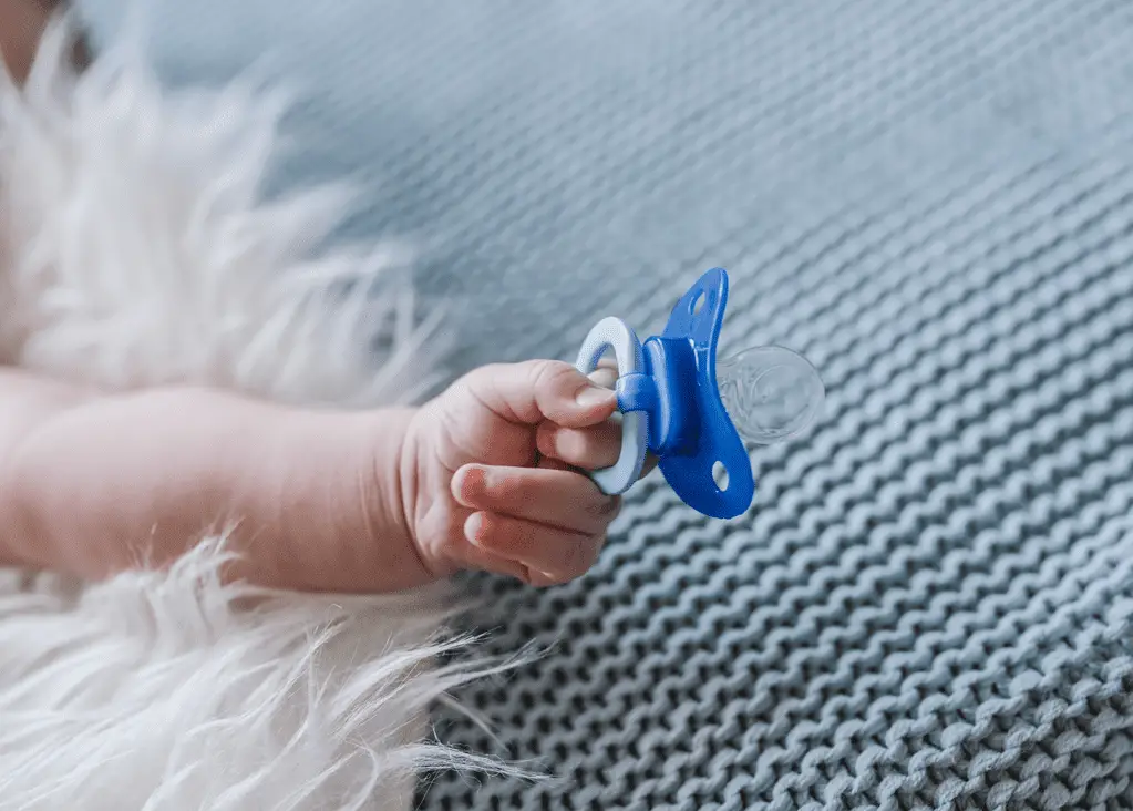 baby holding blue pacifier