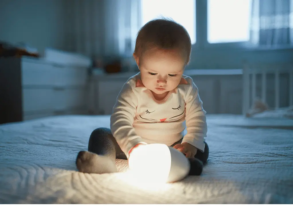 baby holding nightlight in nursery