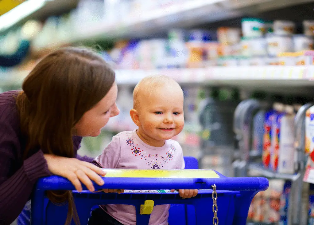 mom smiling at baby in front seat of shopping cart in grocery store