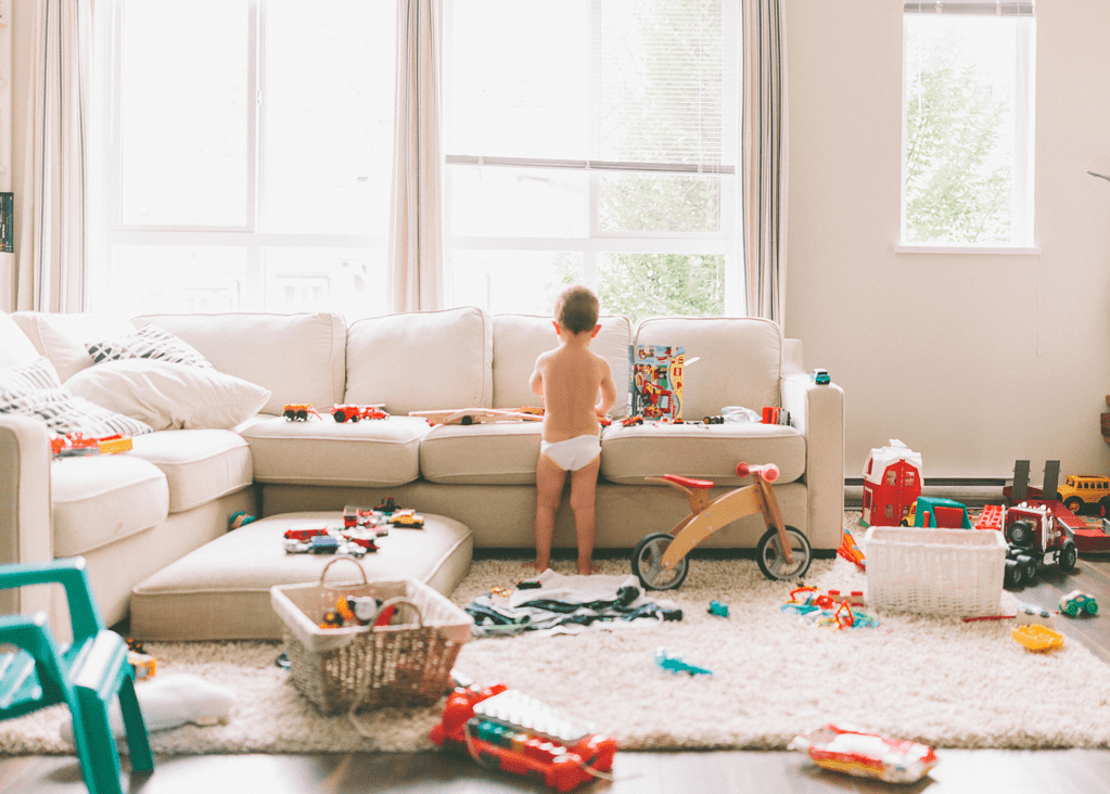 toddler boy playing with toys in cluttered living room