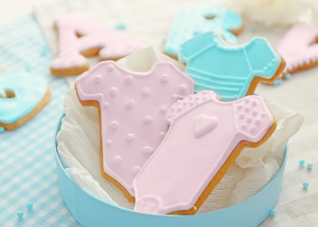 Decorated sugar cookies of a pink and blue onesie as a sneaky way to announce pregnancy