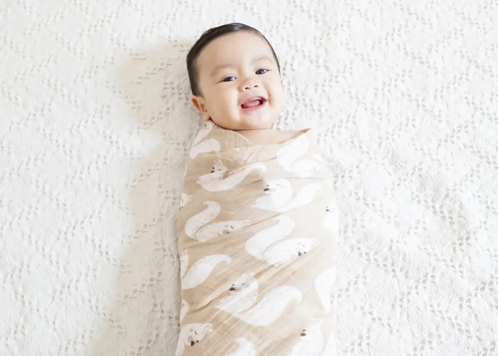 baby smiling while wearing a baby swaddle