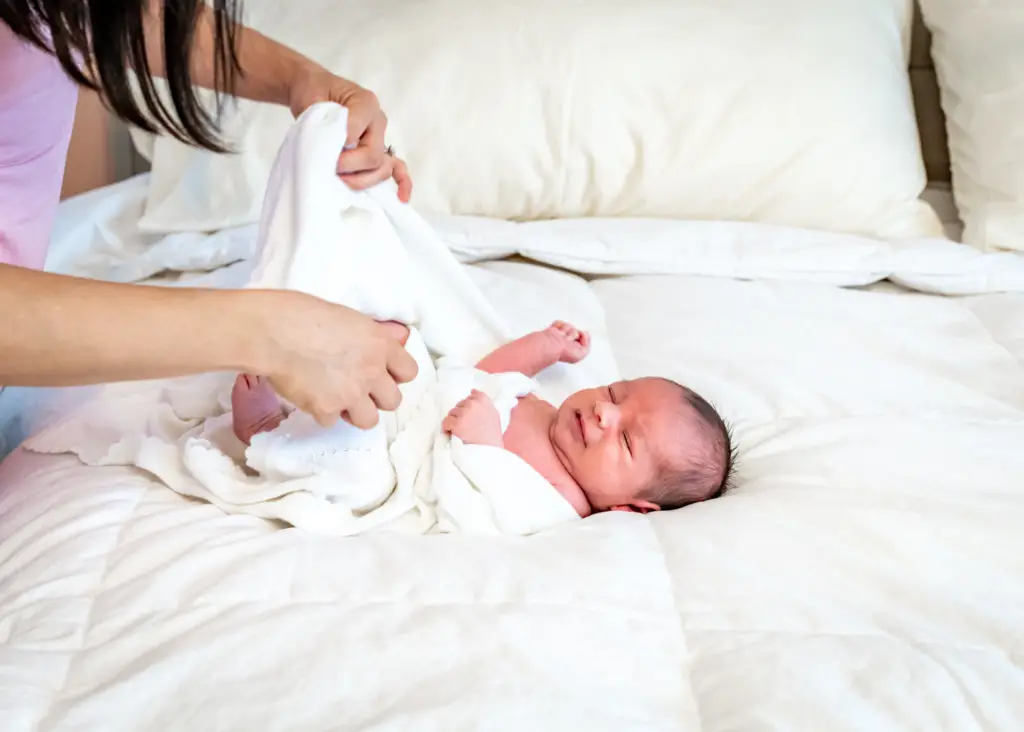 mom trying to swaddle a newborn with baby swaddle