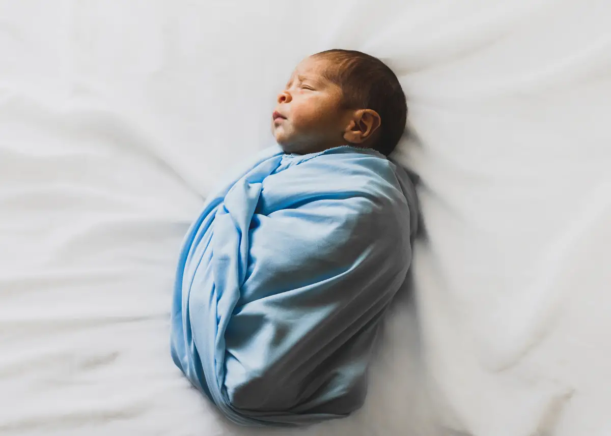 newborn baby wrapped up in blue receiving blanket