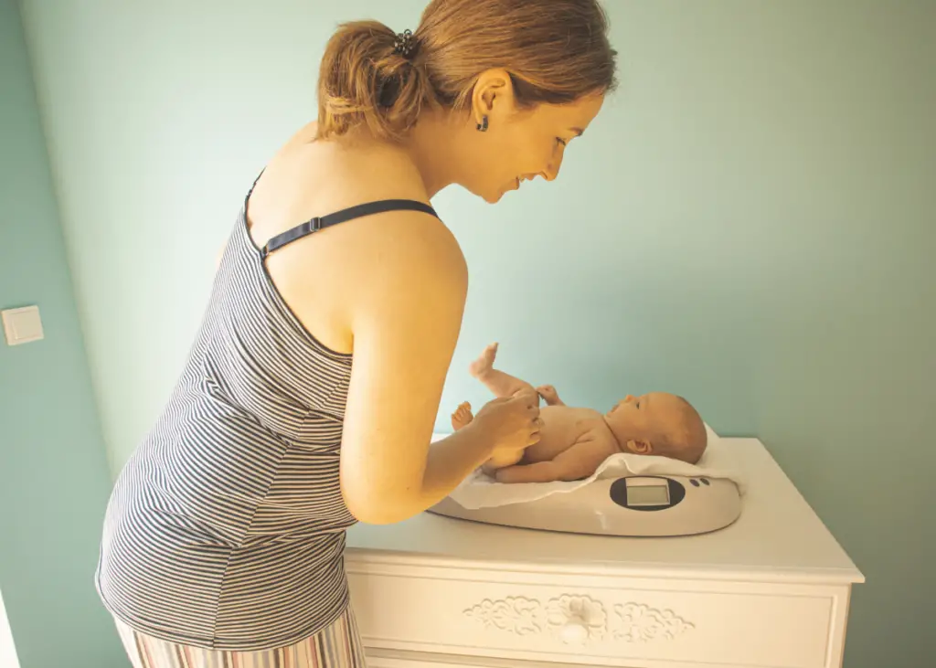 mom weighing baby at home on baby scale