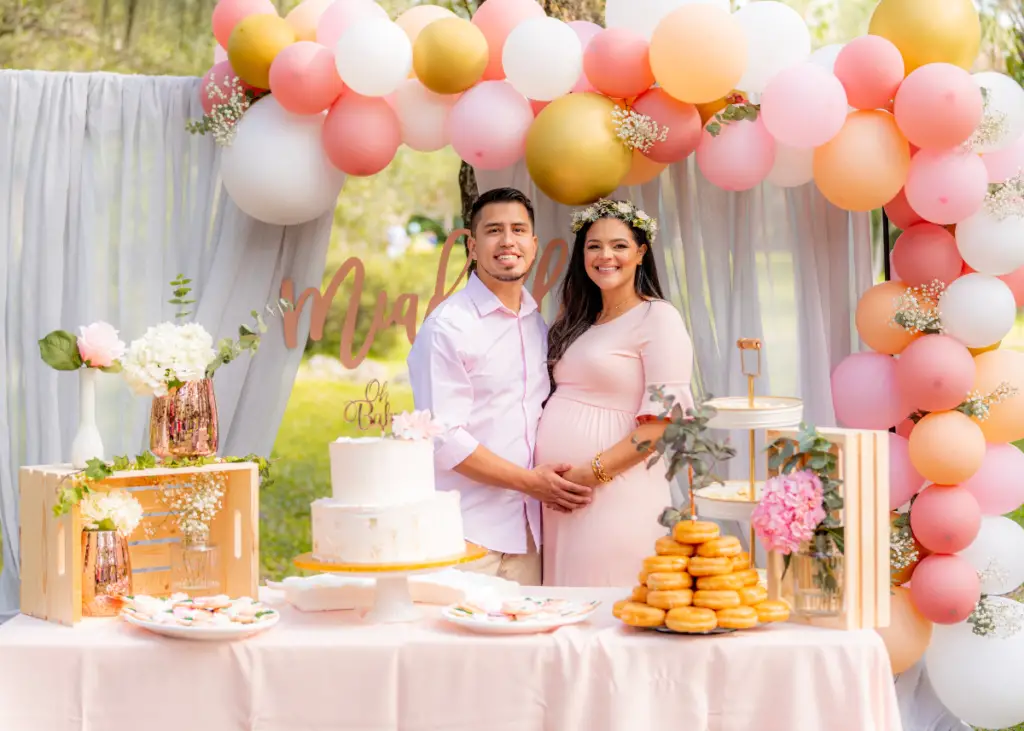 parents-to-be celebrating a baby shower in a park with beautiful balloon arch and dessert table