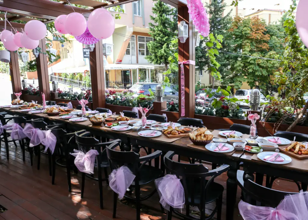 baby shower taking place in a restaurant with a beautiful set long table with pink decorations