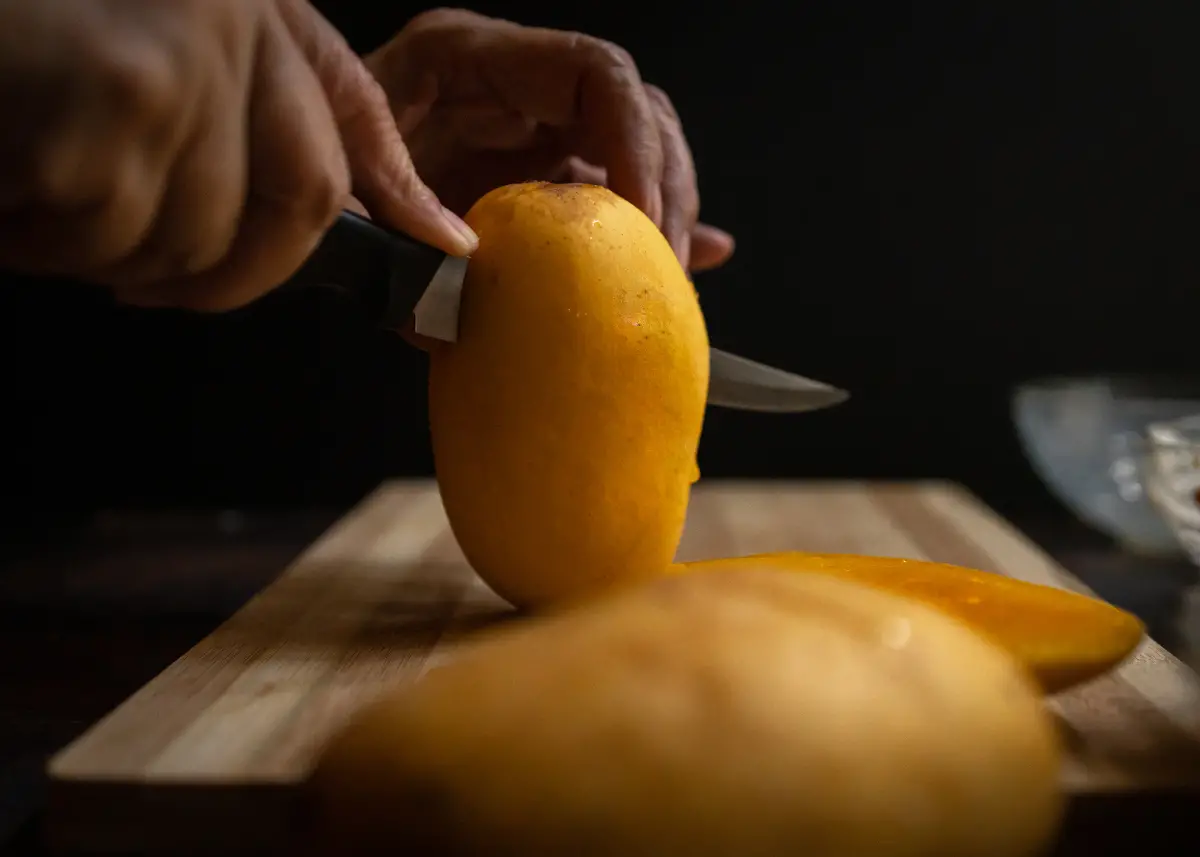 parent cutting mango with sharp knife to serve baby in baby-led weaning