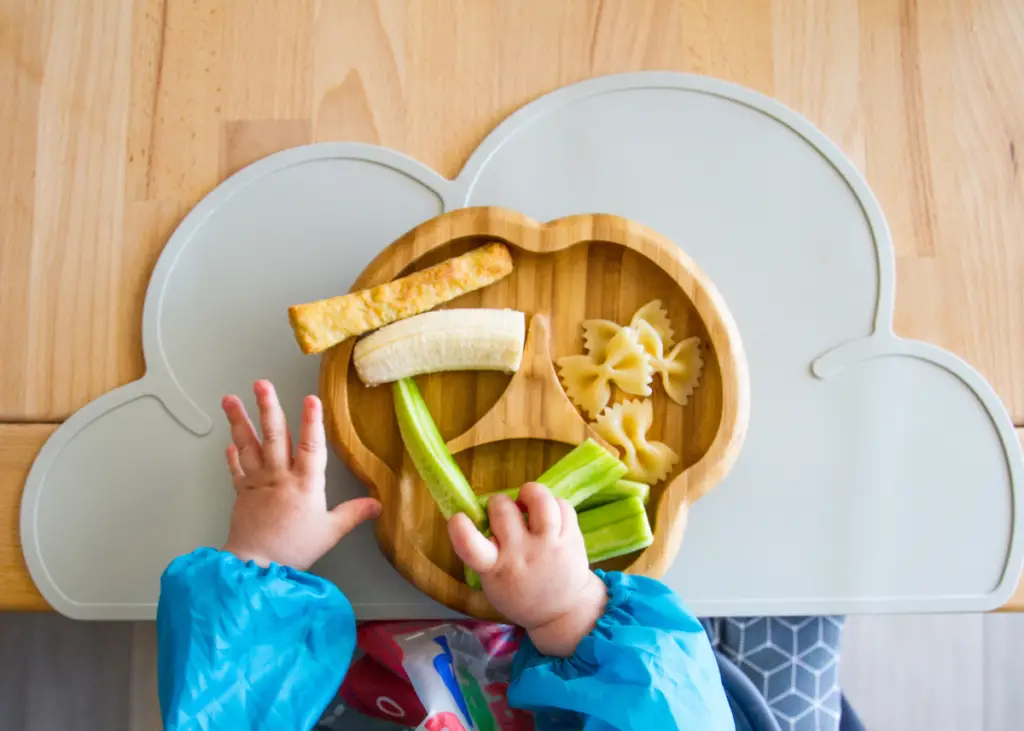 toddler enjoying a meal on a baby led weaning plate