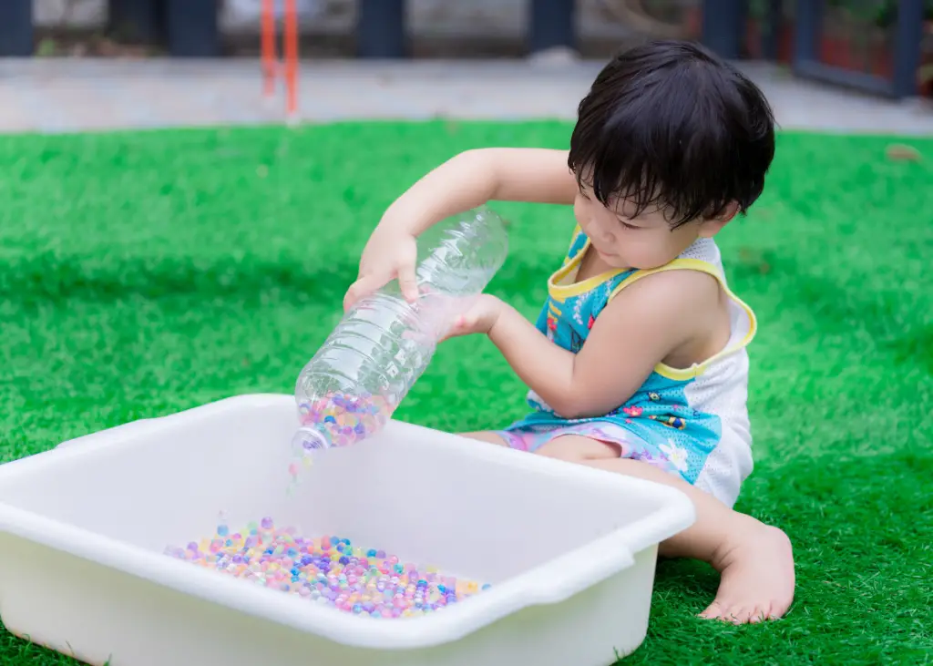 little boy playing with Orbeez water beads in a bin as part of sensory play