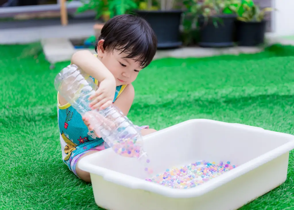 little boy playing with Orbeez water beads in a bin as part of sensory play