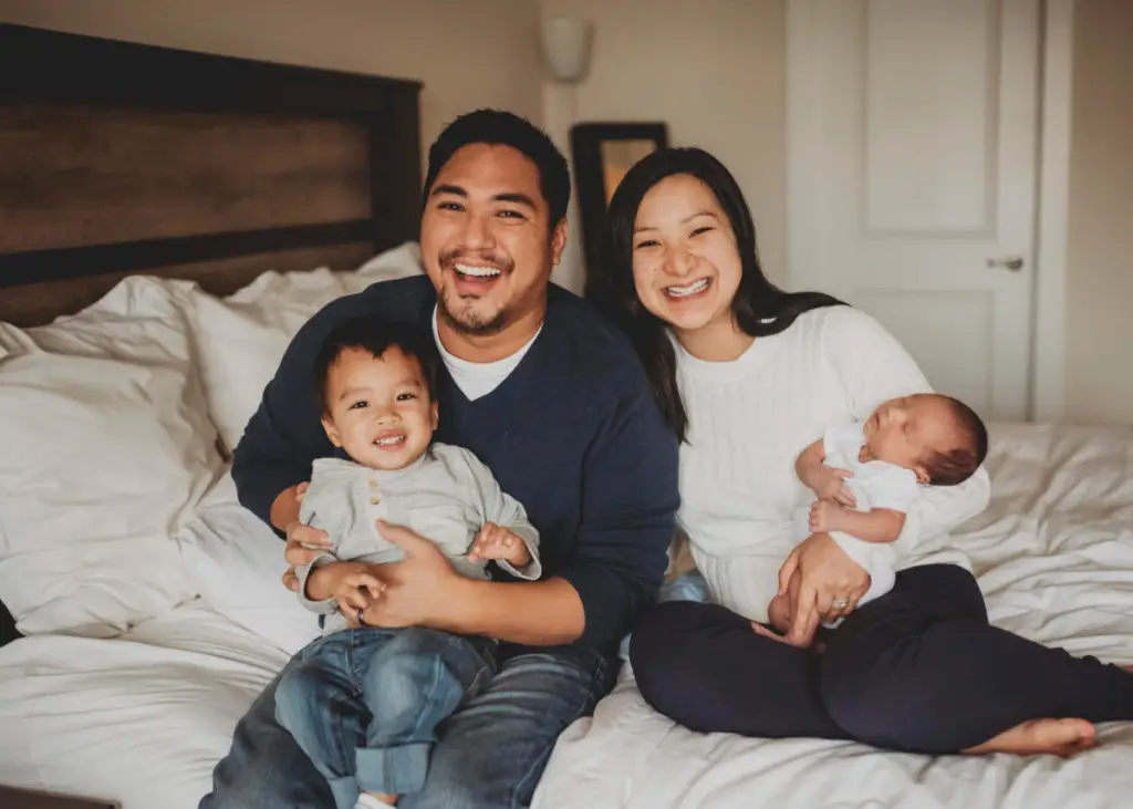 new mom and dad holding newborn baby and older sibling for newborn photoshoot