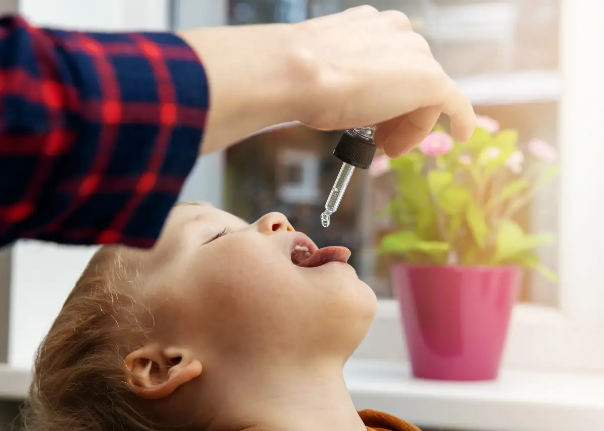 mom giving toddler vitamin D drops with a dropper