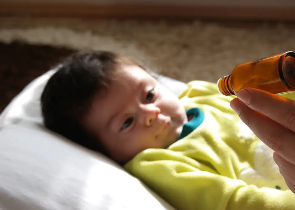 mom giving baby vitamin D drops in a glass dropper