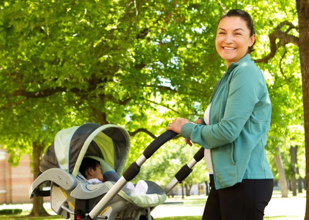 new mom enjoying the summer weather with her newborn baby by taking a walk with a stroller