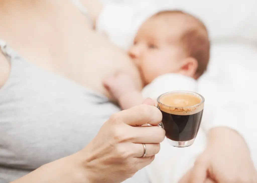 new mom breastfeeding baby holding a coffee, which is not one of the best drinks for breastfeeding moms