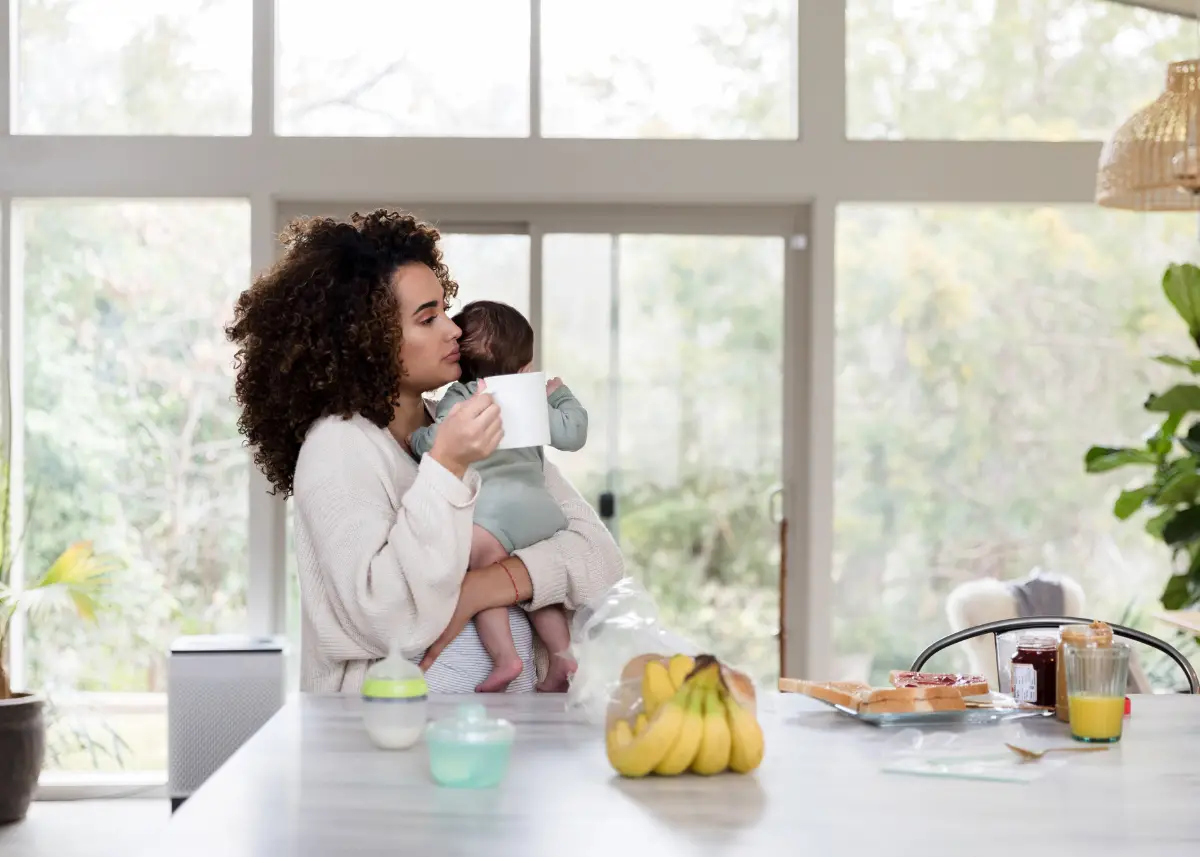 new mom breastfeeding baby drinking herbal tea as one of the best drinks for breastfeeding moms