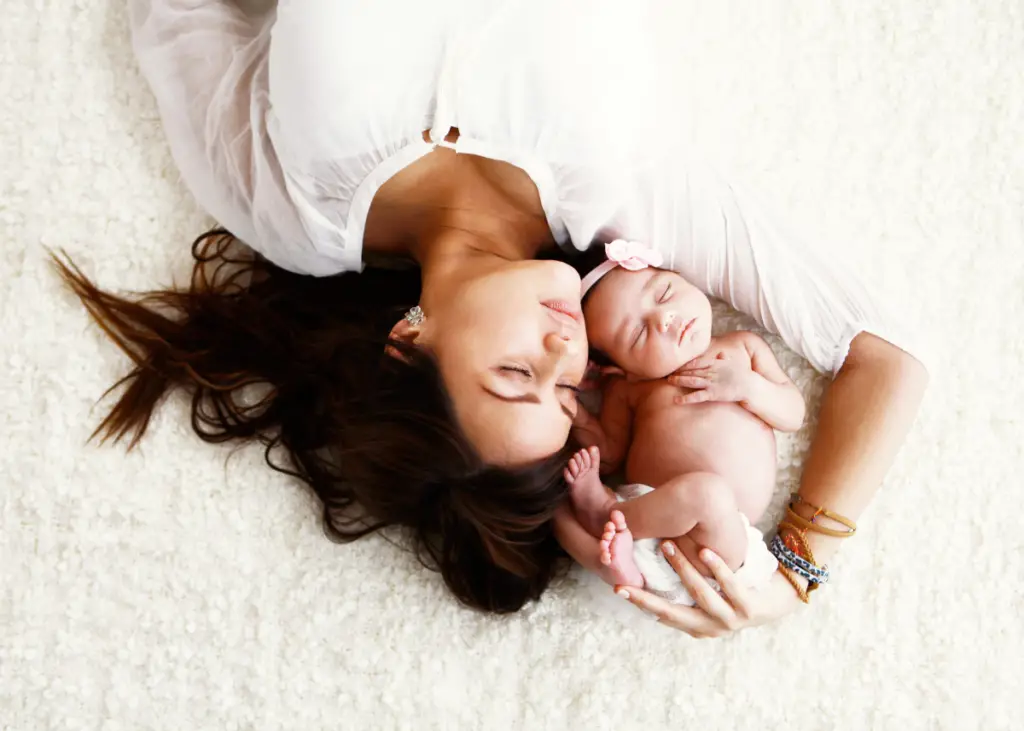 new mom posing with newborn baby girl for newborn photoshoot