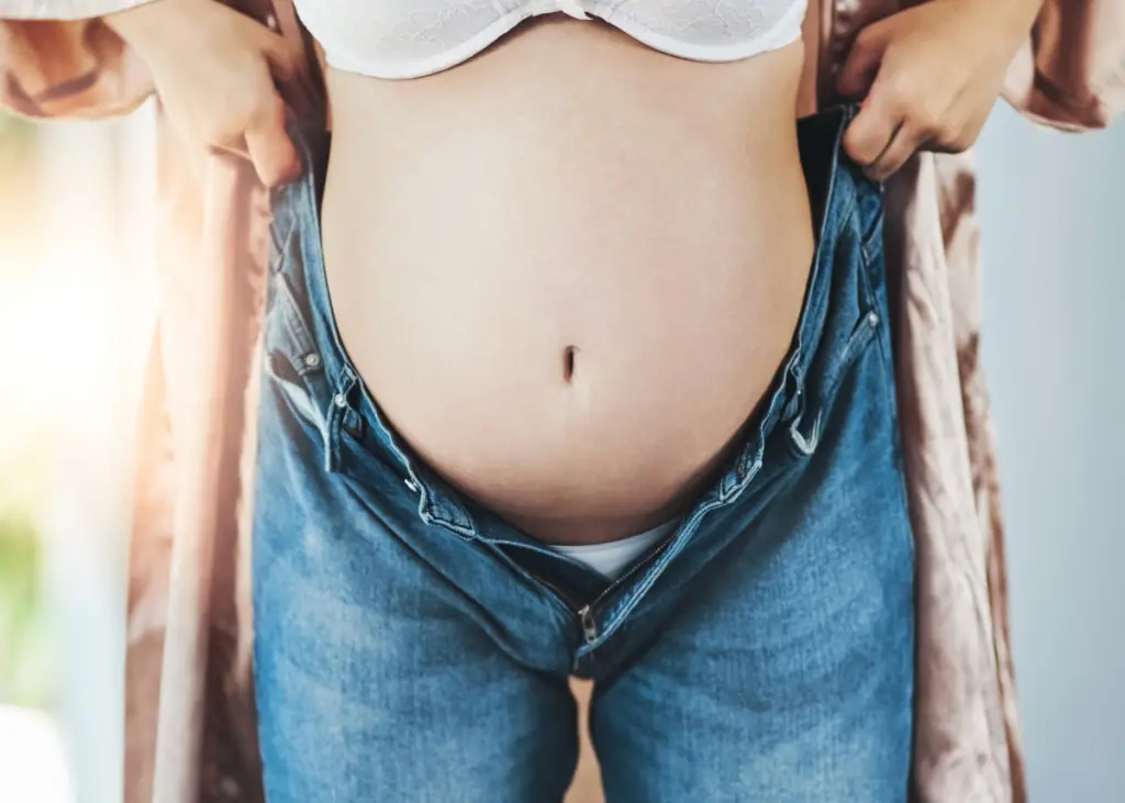 pregnant woman putting on jeans