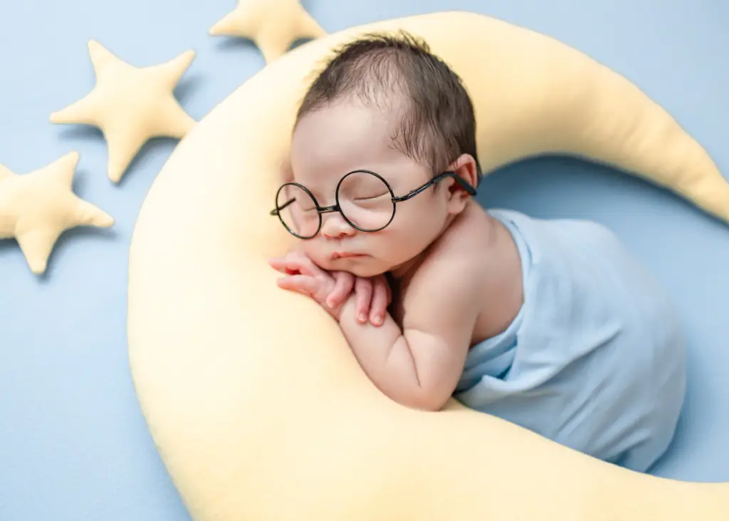 newborn baby posing with props of moon and stars and glasses as part of newborn photography session