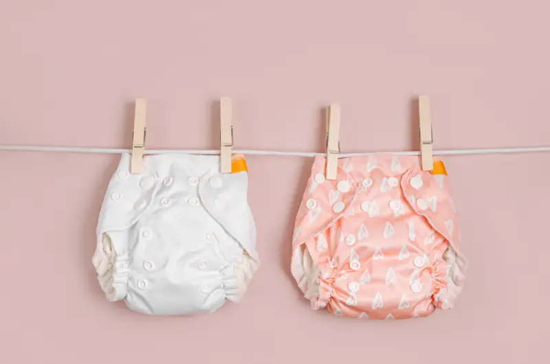 two cloth diapers hanging on a laundry line being prepped for the first time